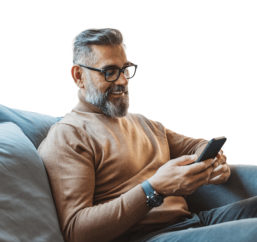 Man relaxes on a couch while checking his phone.